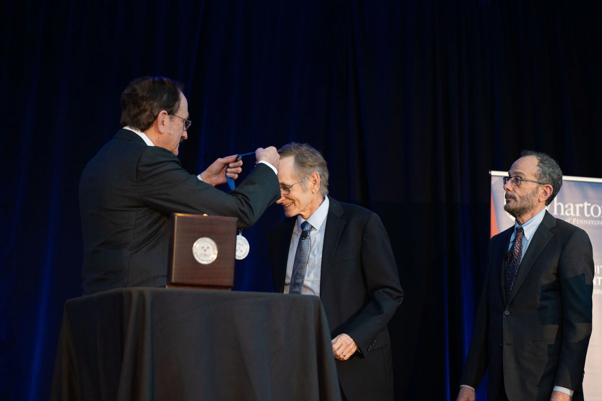 Bruce Jacobs places a medal over Albert S. “Pete” Kyle's head. Ken Levy watches.