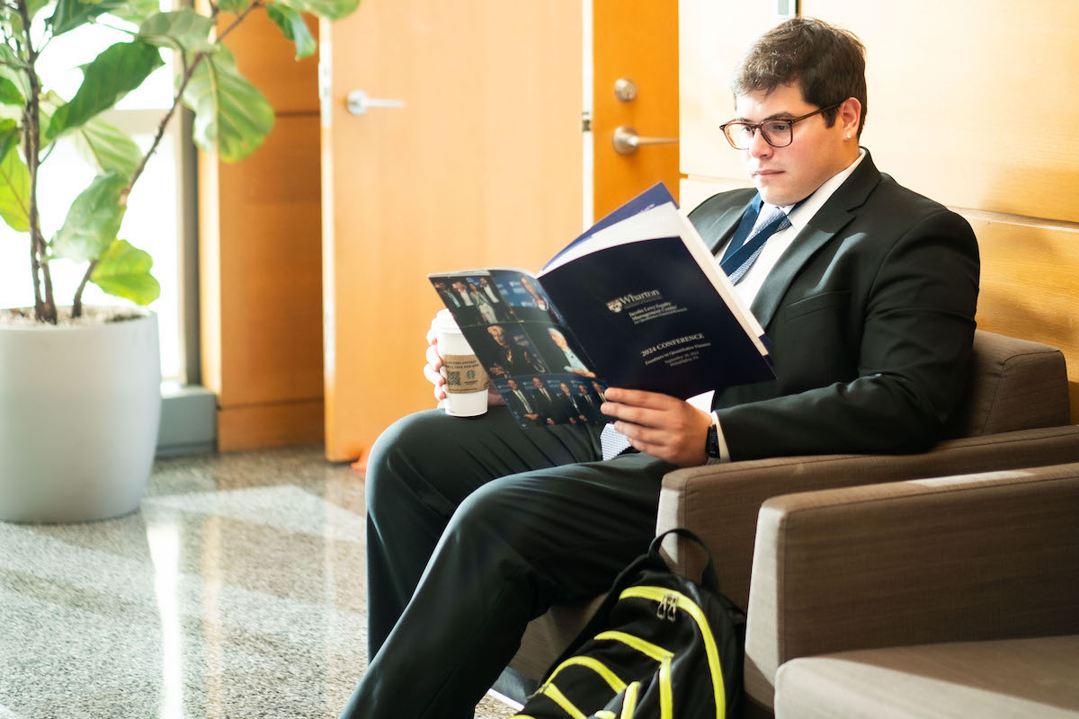 A Frontiers in Quantitative Finance Conference goer reads the program while seated.