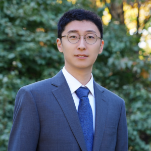 Headshot of a person with glasses before a gray background