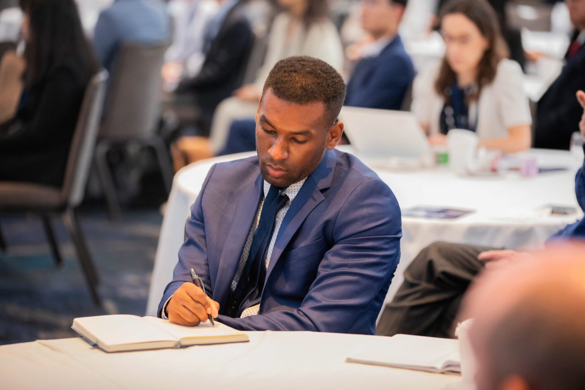 A conference attendee writes into a notebook