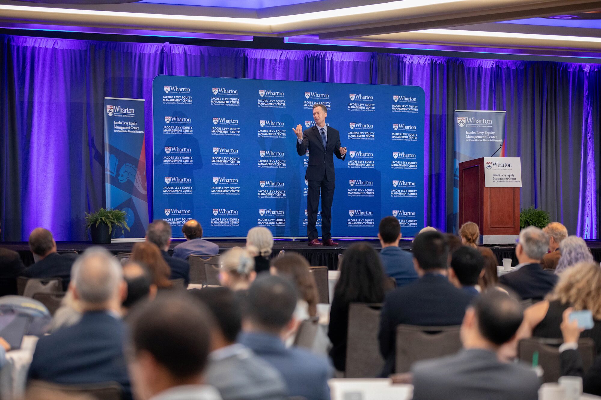 A conference presents to an engaged audience before a blue background