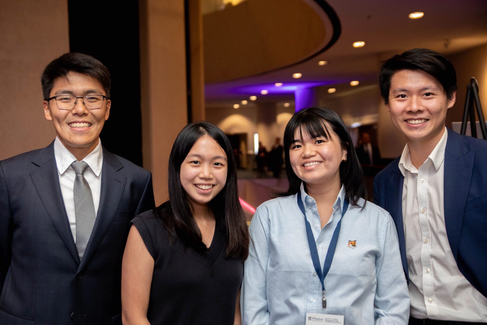 A group of four conference attendees pose for a photo, smiling toward the viewer