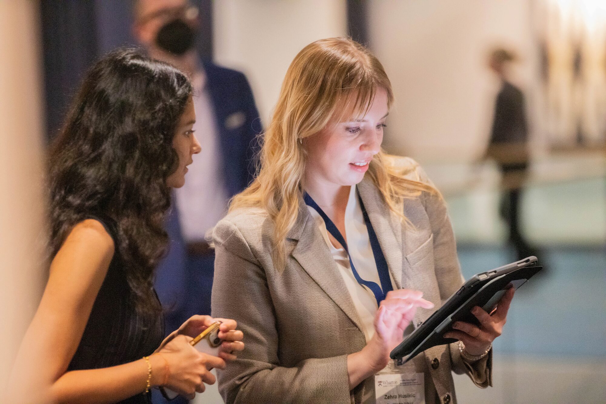 Two people look down into a digital tablet in a professional setting