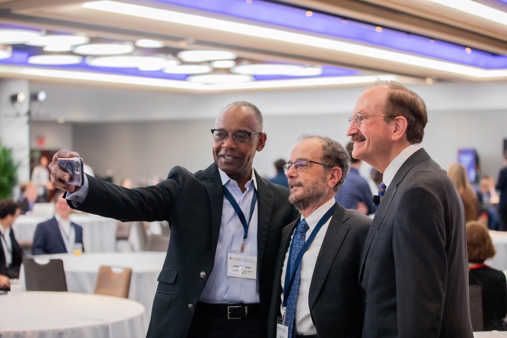 Three people pose for a selfie photo in a conference setting